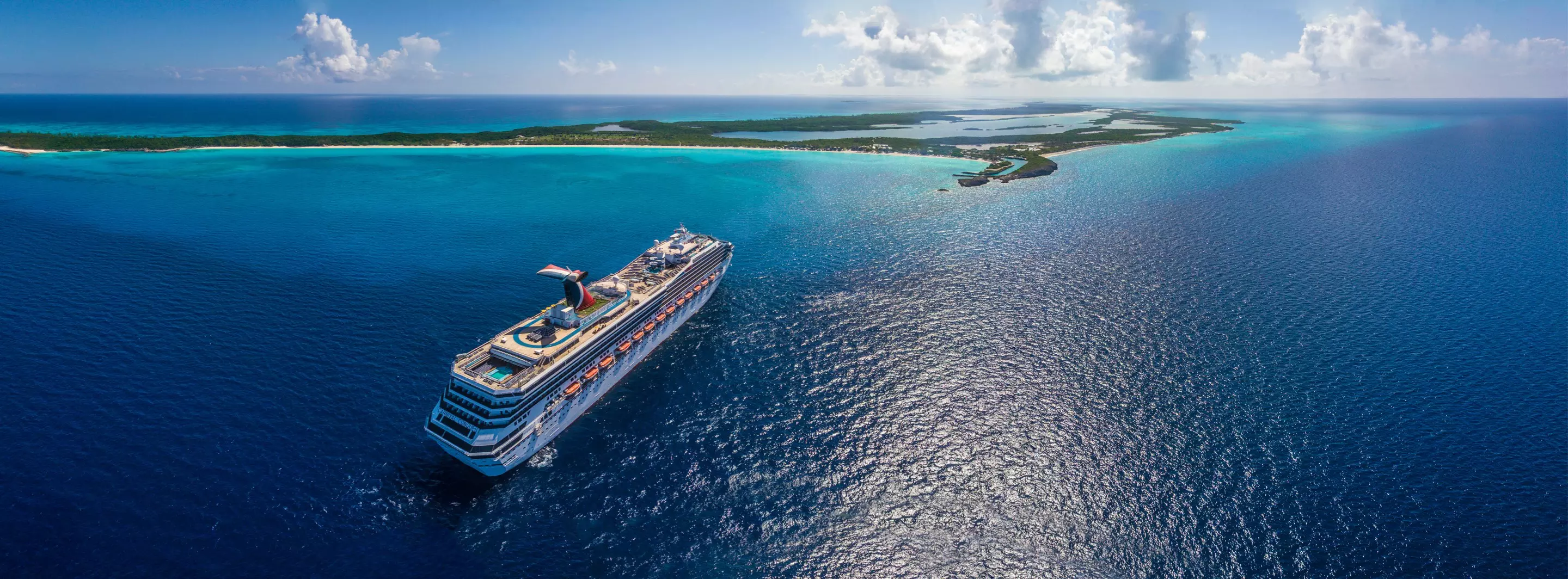 A cruise ship at sea off a low tropical island