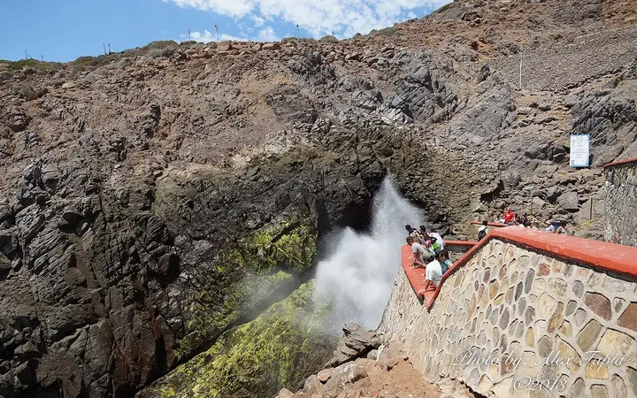 Spray erupting from La Bufadora blowhole beside a stone viewing platform
