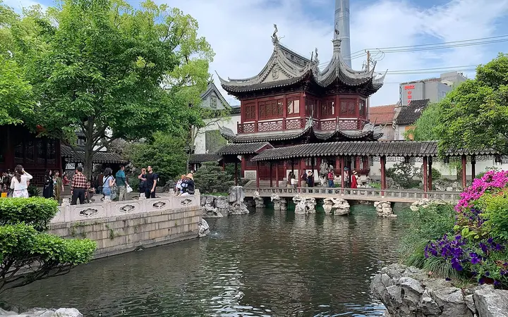 Traditional Chinese pavilion with upturned eaves reflected in a pond surrounded by trees in Yu Garden