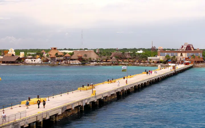 The long concrete cruise pier at Costa Maya leading from the berths to the thatched-roof port complex on shore