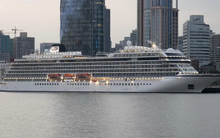 Mid-size cruise ship moored at the North Bund cruise terminal on the Huangpu River with Hongkou high-rises behind
