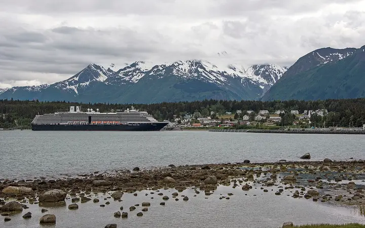 Haines waterfront and the white buildings of Fort William H. Seward below snow-capped mountains, with a cruise ship at the dock