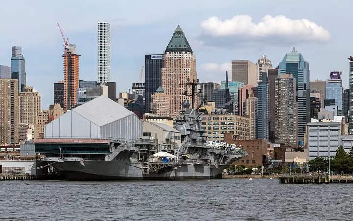 USS Intrepid at Pier 86 on the Hudson River with the Midtown West skyline behind