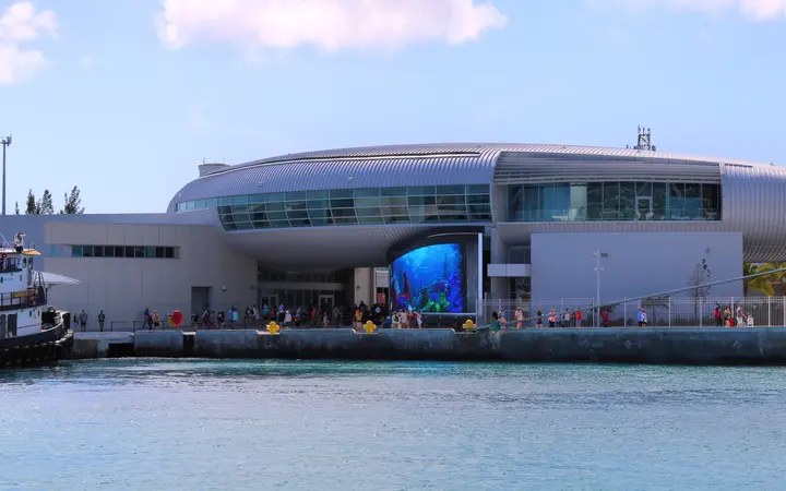 The curved silver Arrivals Terminal building at Nassau Cruise Port, seen from the harbour