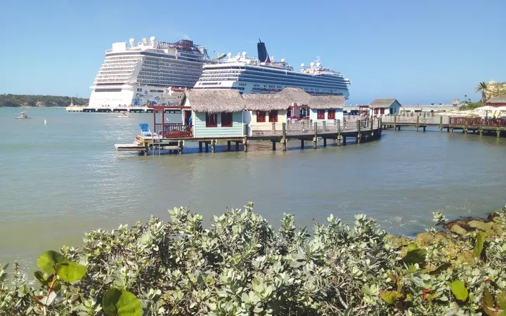 Cruise ships docked at Amber Cove beside over-water buildings on the Bay of Maimón