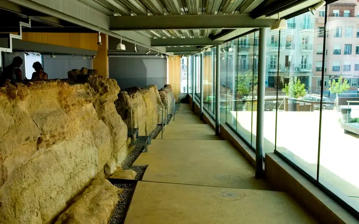 The remains of the Punic Wall inside the glazed Muralla Púnica interpretation centre in Cartagena, lit by daylight through the glass wall