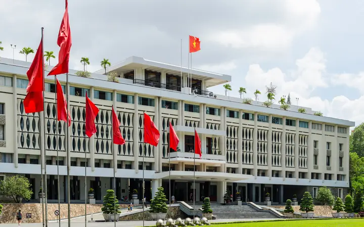 Independence Palace facade with flags under a blue sky