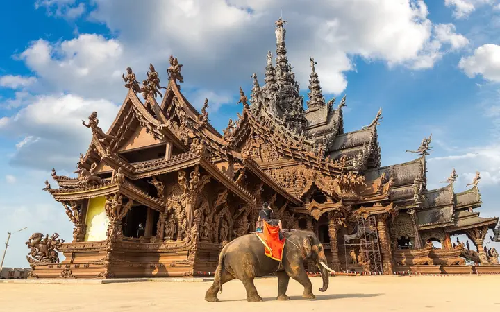 The carved teak spires of the Sanctuary of Truth on the Pattaya waterfront under a bright sky.