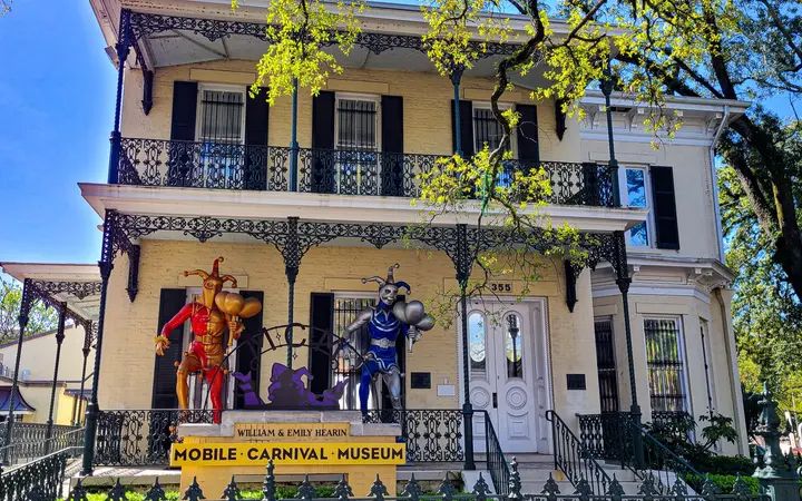The Mobile Carnival Museum's historic house with iron balconies and costumed jester figures out front
