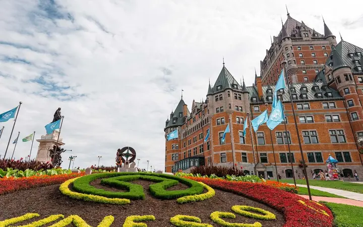 The Château Frontenac's turrets above flower beds spelling UNESCO on a bright day.