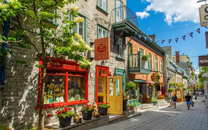 Colourful shopfronts and flowers along the cobbled Rue du Petit-Champlain on a sunny day.