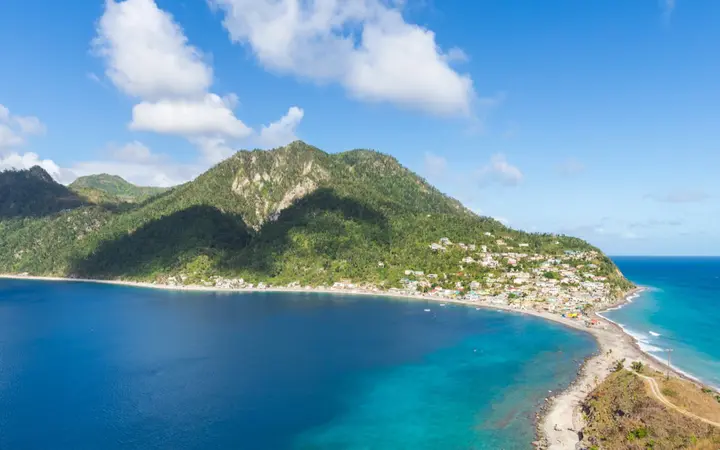 Scotts Head isthmus and Soufrière Bay with turquoise water and green mountains under a blue sky.