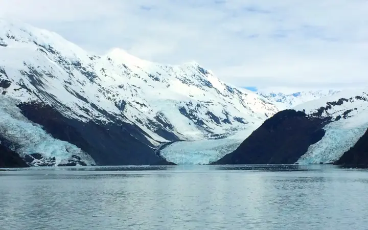 Tidewater glaciers flowing down snowy mountains into the calm waters of Prince William Sound