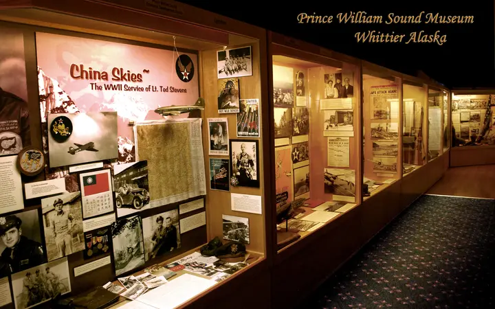 Lit display cases of World War II photographs and memorabilia inside the Prince William Sound Museum in Whittier