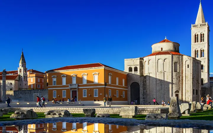 The round stone St Donatus Church and the cathedral bell tower under a blue sky in Zadar